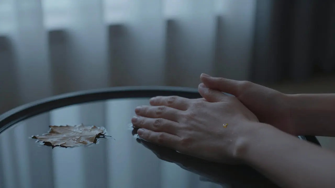 Ruce klidně leží na srdci v tiché noční místnosti, jen světlo z oken a jedna kapička oleje na zápěstí.